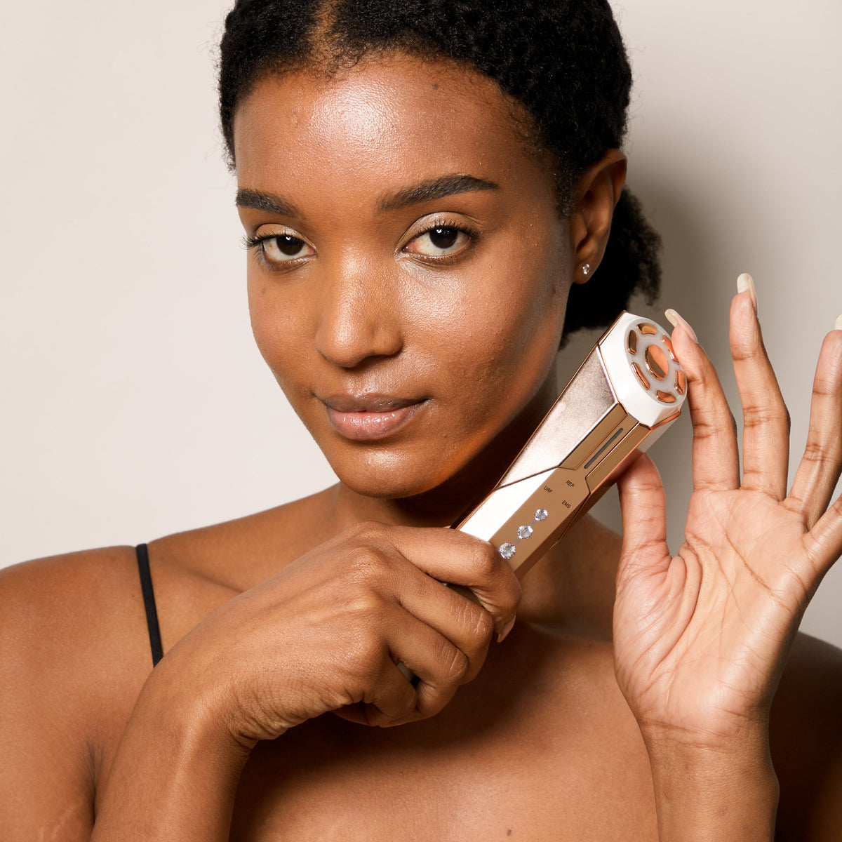 Close-up of a model holding a REVA Instant Age Renewal Wand from Project E Beauty used for non-invasive facial sculpting.