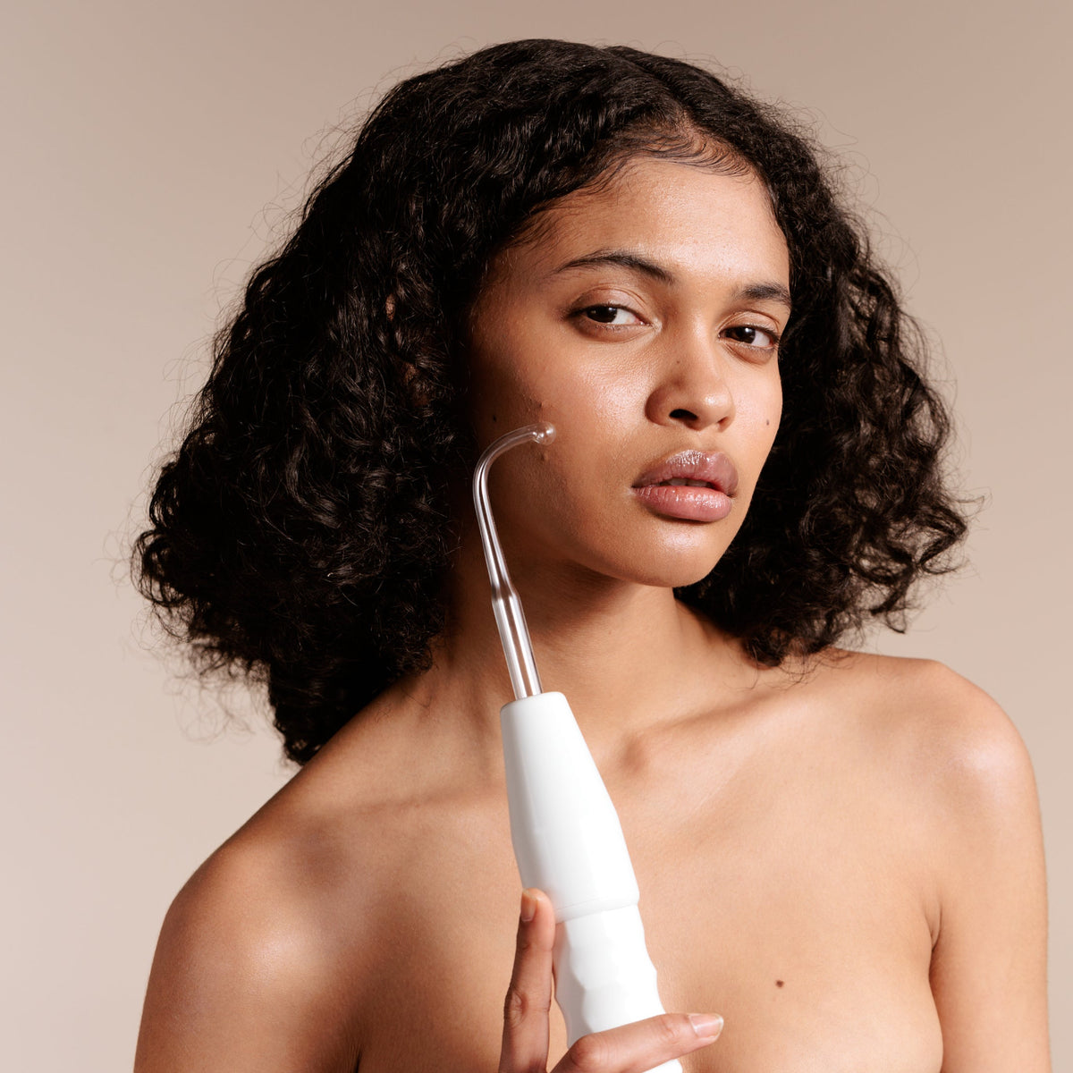Faisca high frequency wand being used by a woman for at-home acne prevention and blemish control.