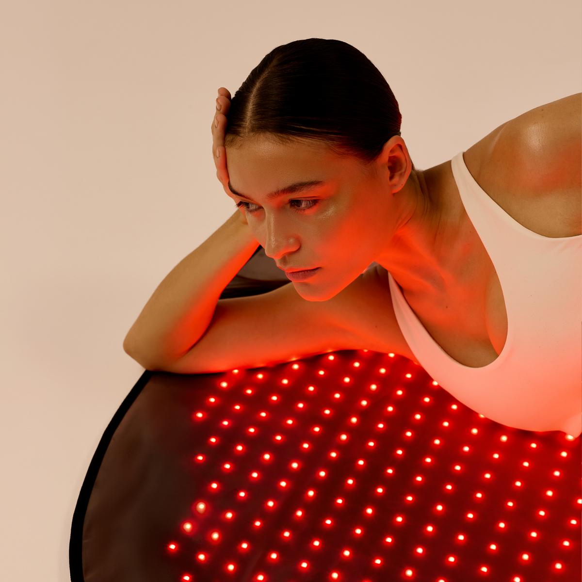 Femme reposant sur un tapis LED Restora allumé, le haut du corps soutenu par les bras